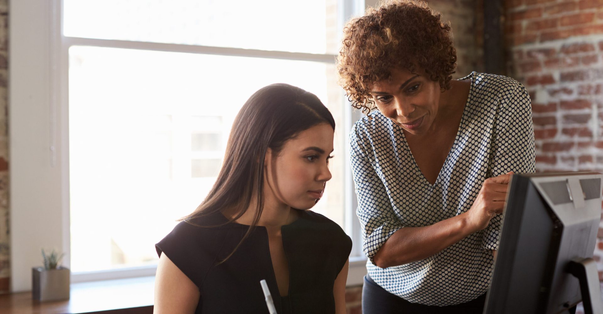 Two Businesswomen Working On Computer In Office