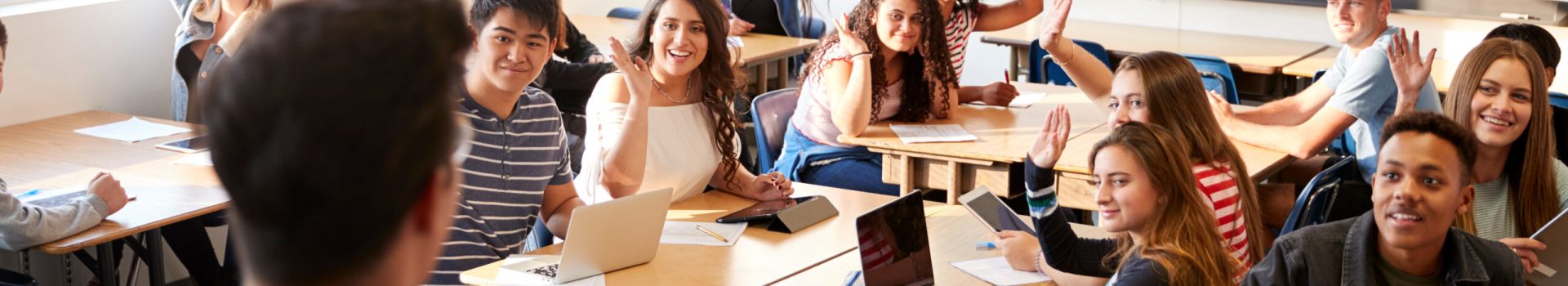 Rear View Of Male High School Teacher Standing At Front Of Class Teaching Lesson