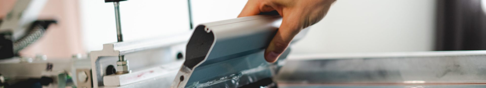 Cropped view of artisan holding squeegee with plastisol ink while working with screen printing machine in designer studio